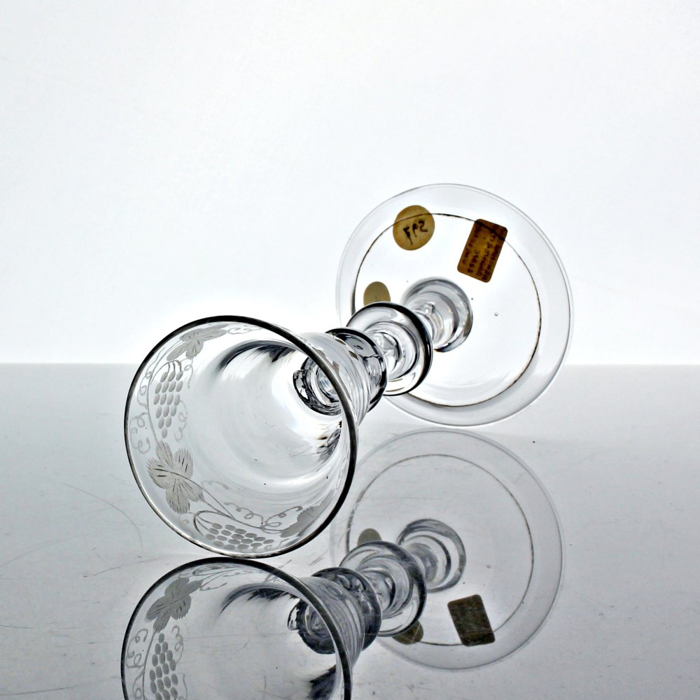 A clear Georgian lead glass wine goblet featuring an engraved vine motif around a pan-topped bowl and a multi-knopped stem. View II