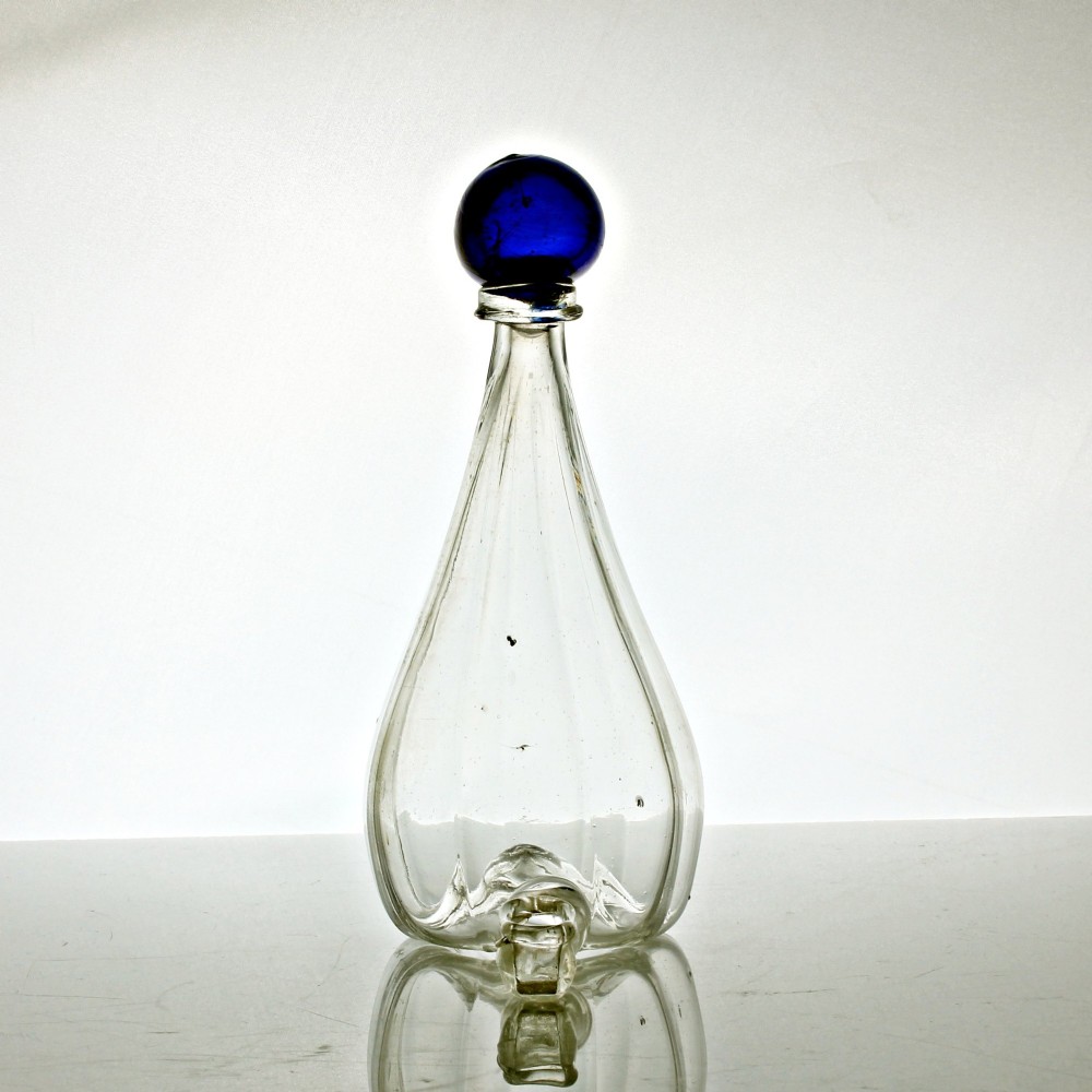A clear ribbed glass conical bird feeder featuring an attached side drinking spout and topped with a solid cobalt blue glass spherical finial. View II