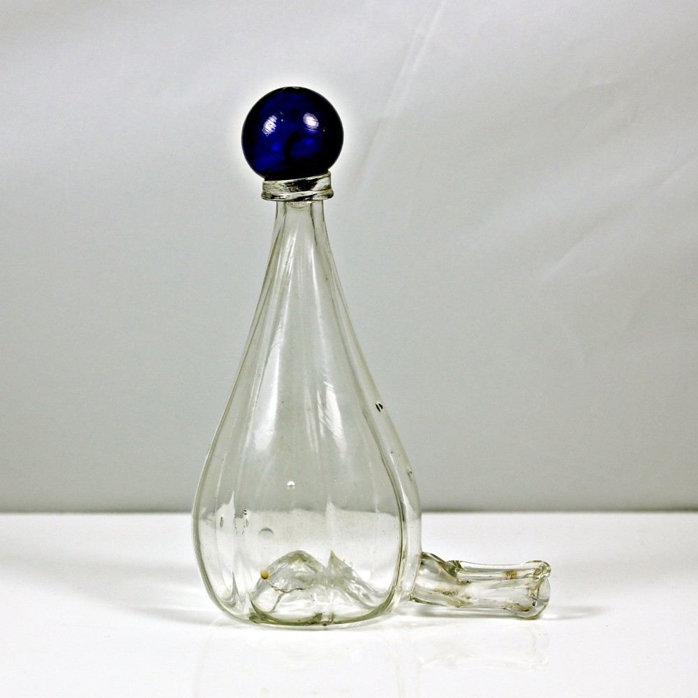 A clear ribbed glass conical bird feeder featuring an attached side drinking spout and topped with a solid cobalt blue glass spherical finial. View III