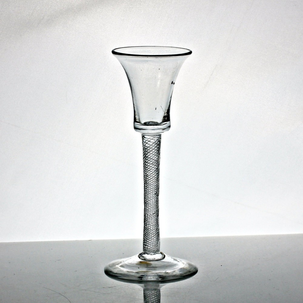 An eighteenth-century clear lead glass wine glass featuring a waisted bucket bowl, a multi-spiral air twist stem, and a flat conical foot.