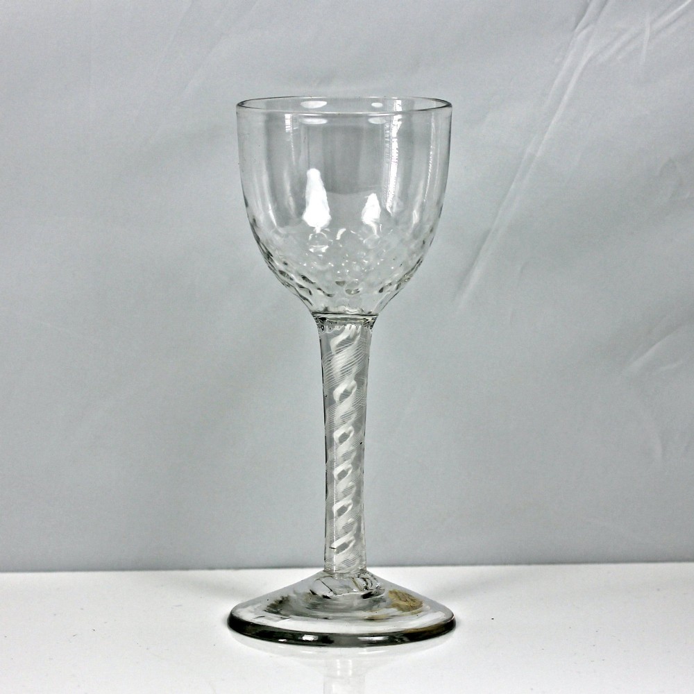 An 18th-century Georgian clear glass goblet featuring an ovoid bowl with basal mouldings, a double series opaque twist stem, and a flat conical foot.