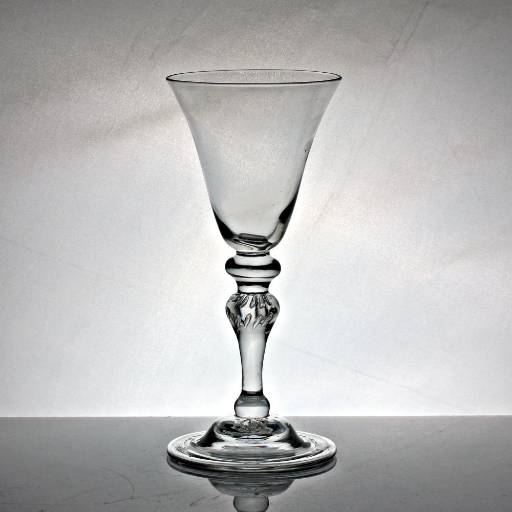 A clear Georgian glass goblet featuring a bell-shaped bowl, a turned baluster stem with knops, and a domed circular foot.