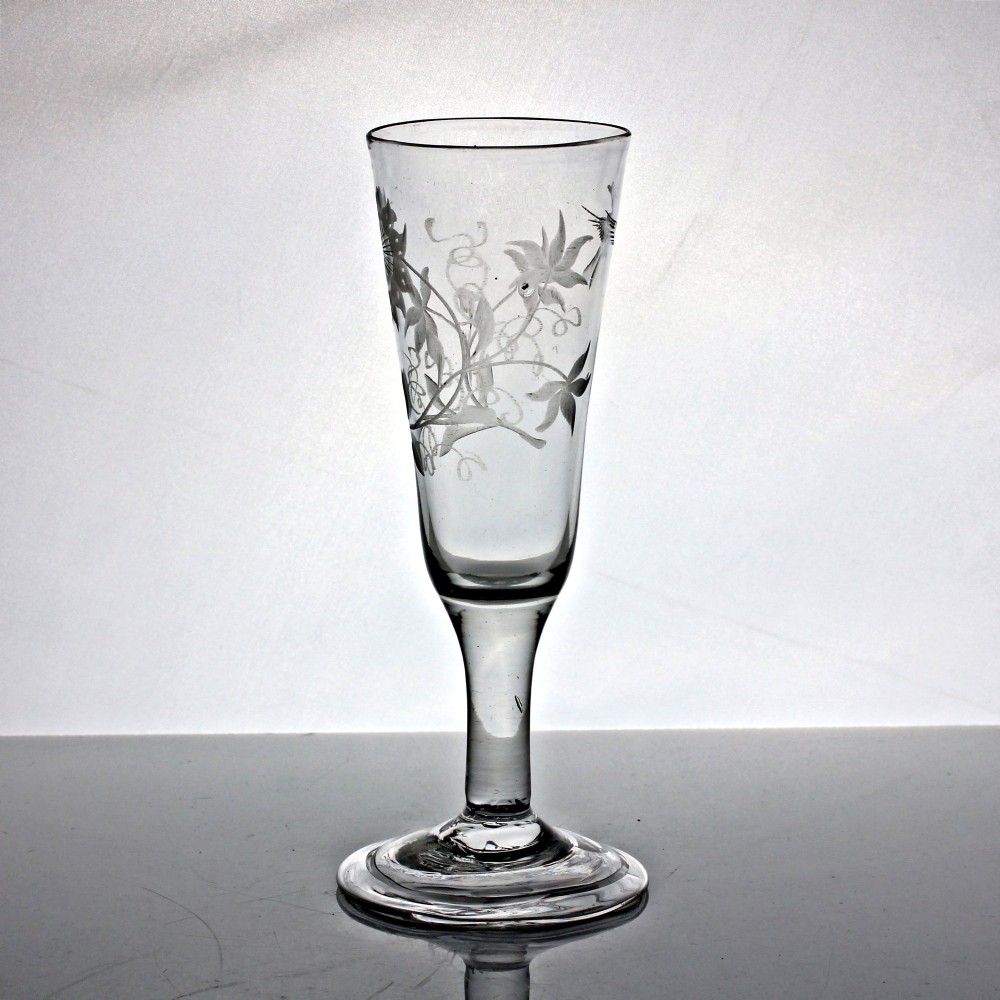 A Georgian clear lead glass ale flute featuring a plain stem, a folded foot, and a wheel-engraved passion flower motif on the bowl. View IV