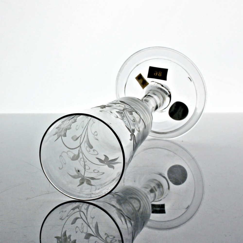 A Georgian clear lead glass ale flute featuring a plain stem, a folded foot, and a wheel-engraved passion flower motif on the bowl. View V
