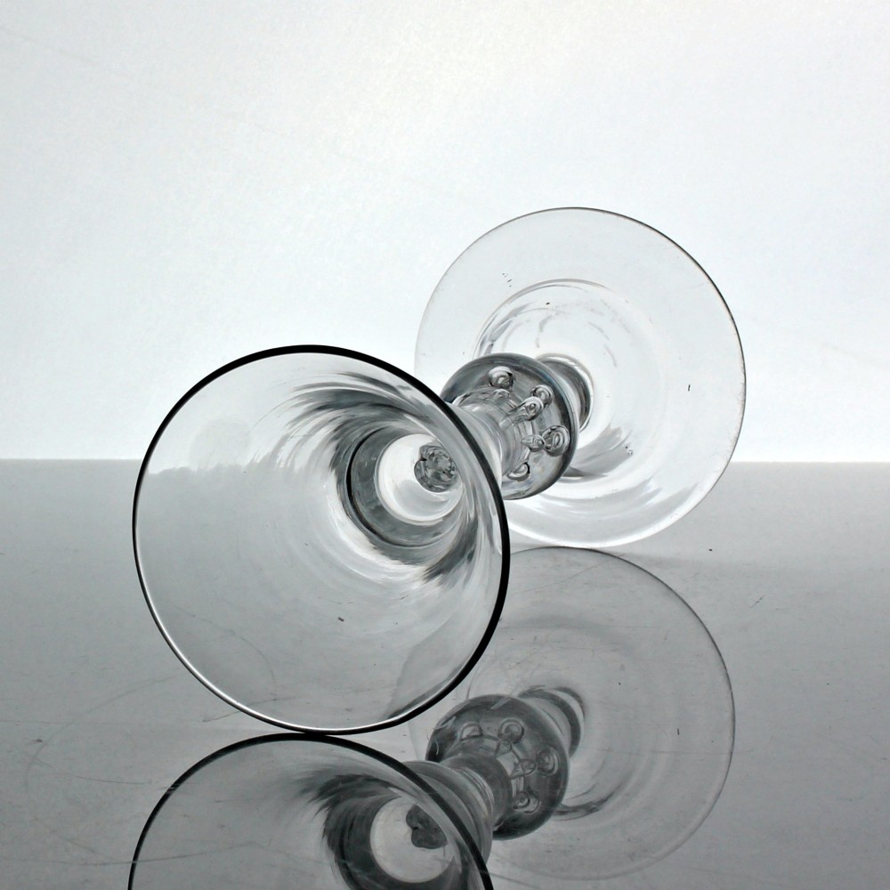 A clear hand-blown Georgian glass stemware piece with a bell bowl, a medial air tear knop, and a wide flat foot. View II