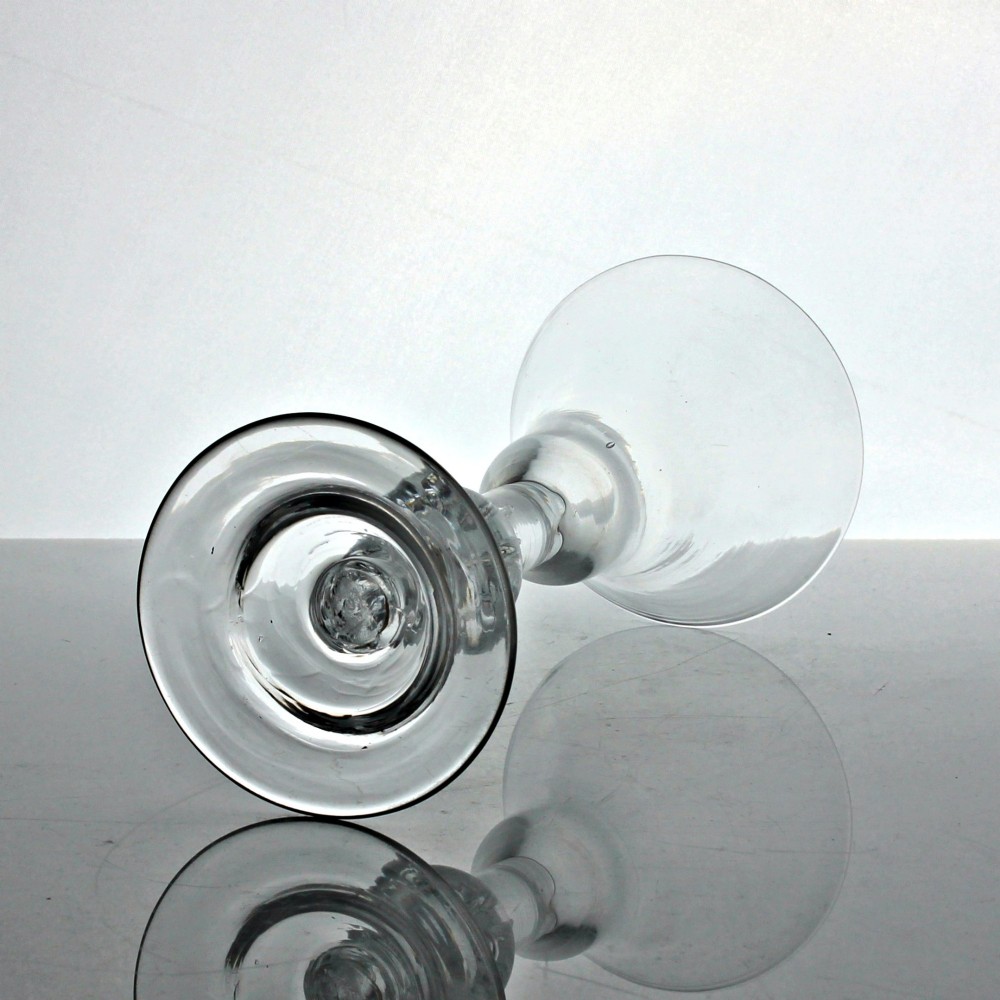 A clear hand-blown Georgian glass stemware piece with a bell bowl, a medial air tear knop, and a wide flat foot. View III