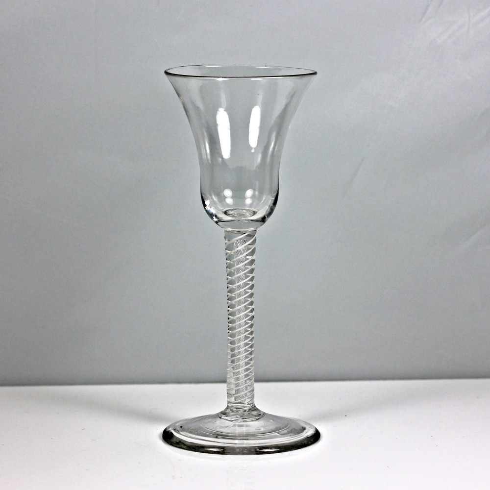 A clear Georgian glass goblet featuring a flared bell bowl resting on a tall mixed-twist stem and circular base.