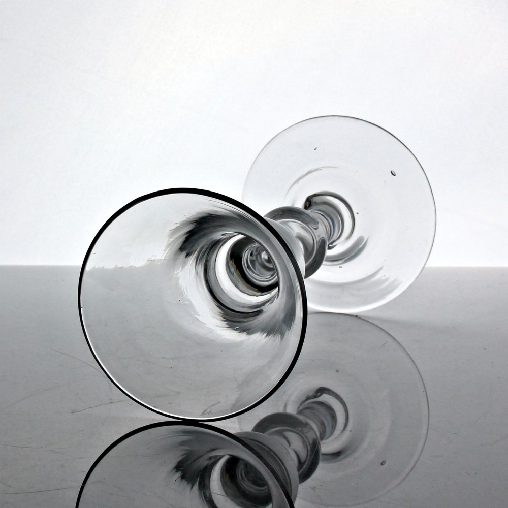 An 18th-century clear glass wine glass featuring a flared bell-shaped bowl, a turned baluster stem with knops, and a wide domed foot. View II