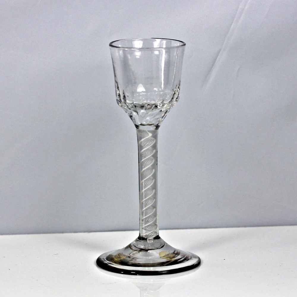 A Georgian clear glass wine goblet featuring a wrythened ogee bowl, a double series opaque twist stem, and a circular conical foot.