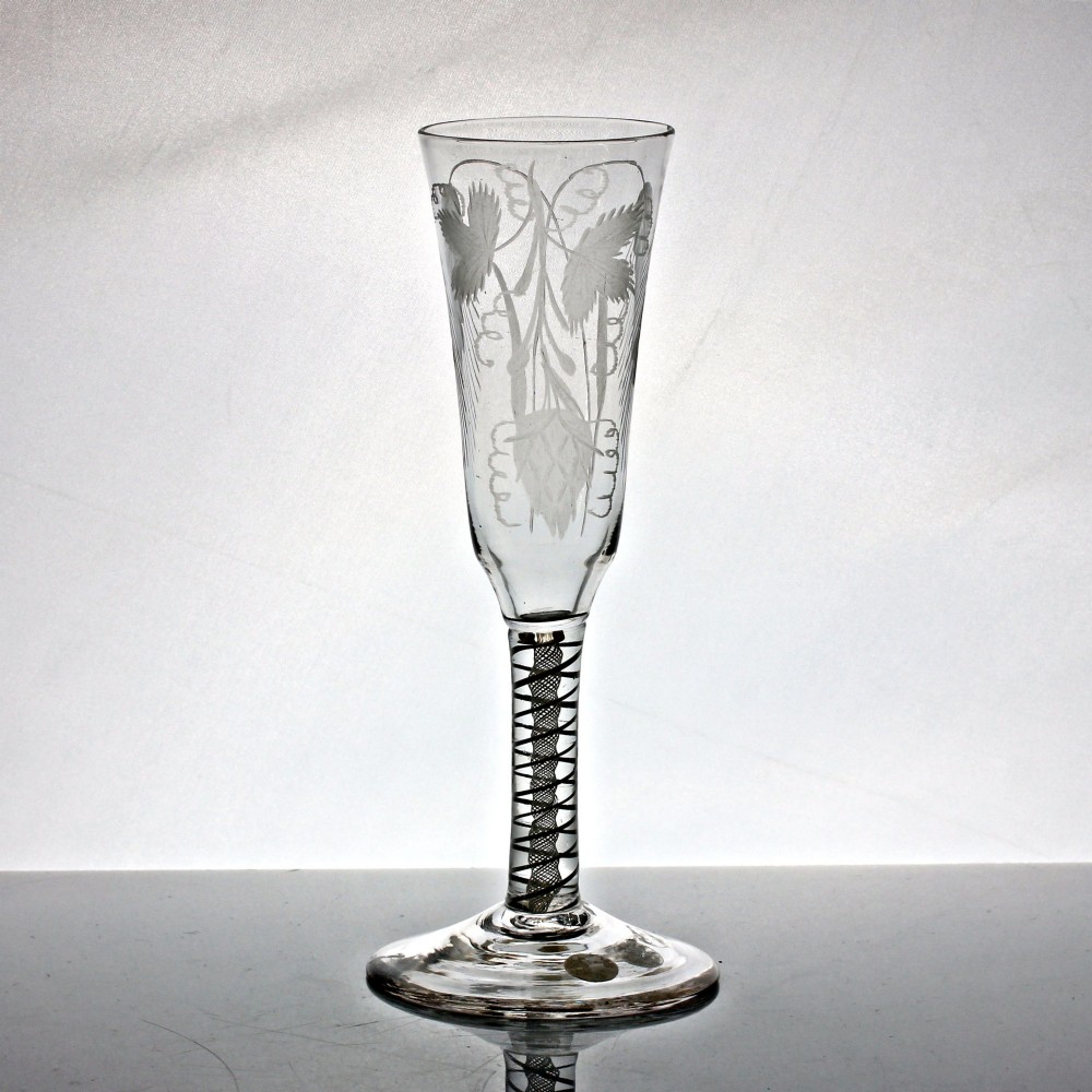 An antique clear glass ale flute featuring a double series opaque twist stem and an engraved hop and barley motif on the bowl. View II