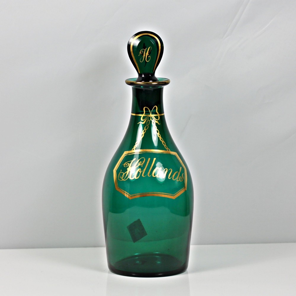A set of three Georgian Bristol green glass decanters with gilded labels for Brandy, Hollands, and Rum, featuring monograms on the disc stoppers. View V