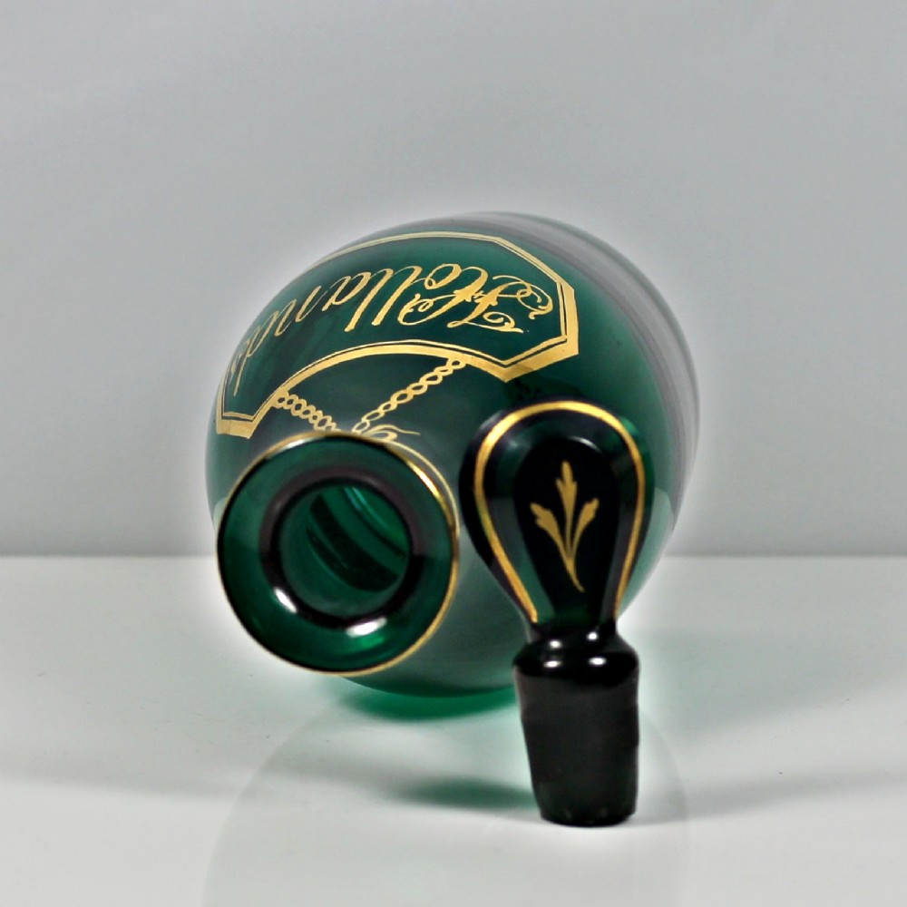 A set of three Georgian Bristol green glass decanters with gilded labels for Brandy, Hollands, and Rum, featuring monograms on the disc stoppers. View VI