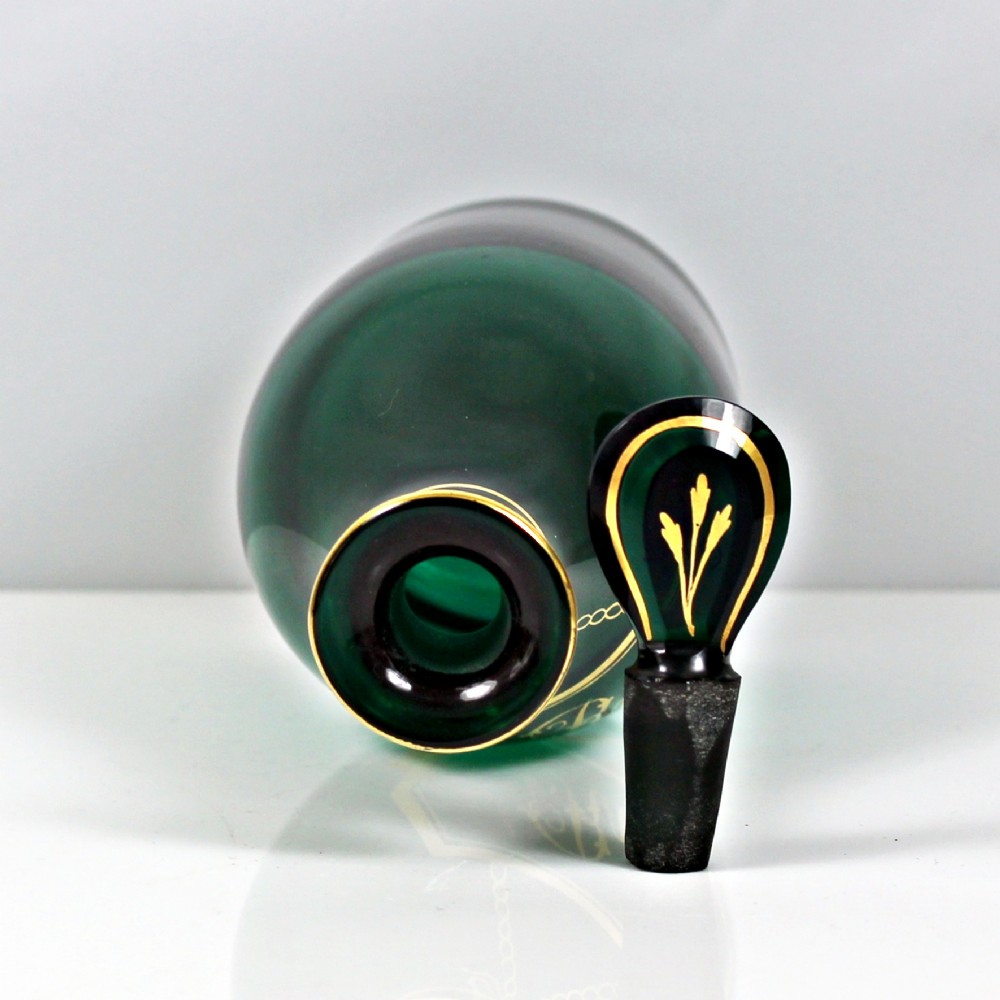 A set of three Georgian Bristol green glass decanters with gilded labels for Brandy, Hollands, and Rum, featuring monograms on the disc stoppers. View IX