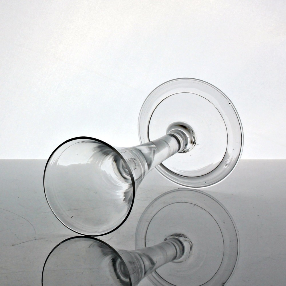 An 18th-century clear glass wine glass with a funnel-shaped bowl, a plain stem featuring an air tear drop inclusion, and a wide folded foot. View II