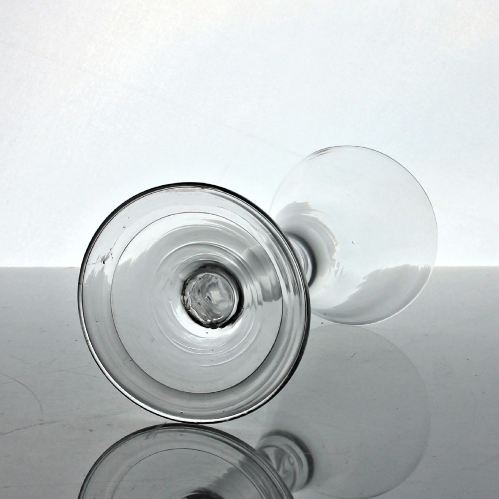 An 18th-century clear glass wine glass with a funnel-shaped bowl, a plain stem featuring an air tear drop inclusion, and a wide folded foot. View III