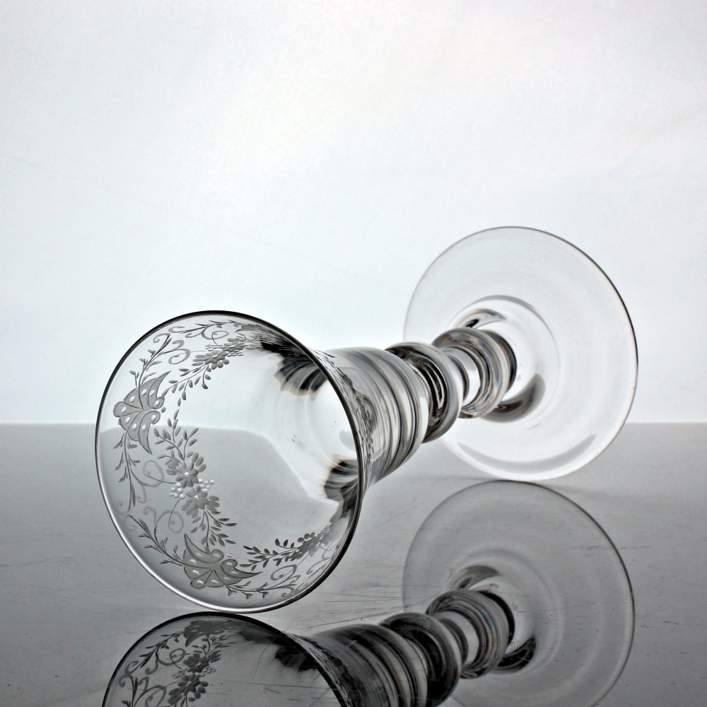 A clear Georgian lead glass goblet featuring a bell-shaped bowl with wheel-engraved floral and bird motifs, supported by a heavy baluster stem on a domed foot. View II