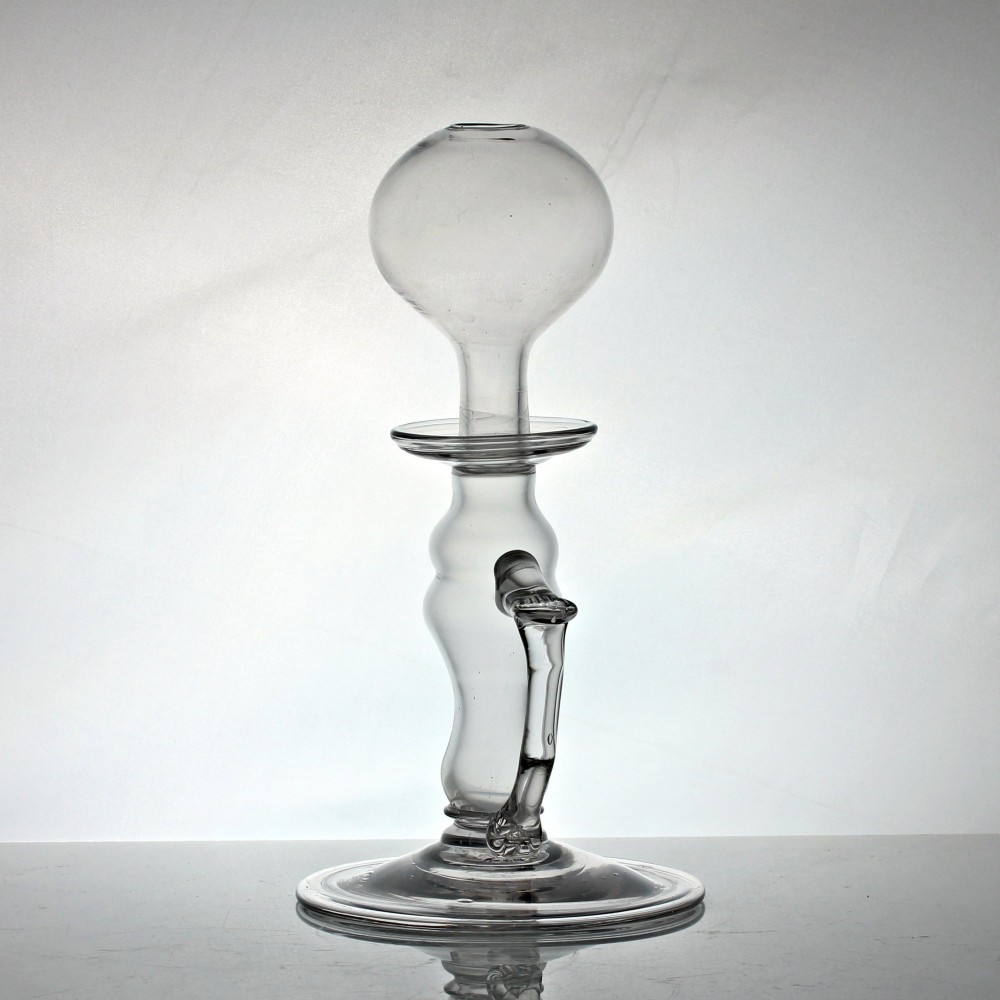 A tall clear hand-blown glass Georgian oil lamp featuring a bulbous top reservoir, a drip tray, a baluster stem, and an applied side handle on a broad circular foot. View II
