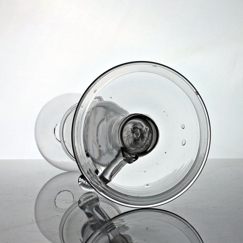 A tall clear hand-blown glass Georgian oil lamp featuring a bulbous top reservoir, a drip tray, a baluster stem, and an applied side handle on a broad circular foot. View IV