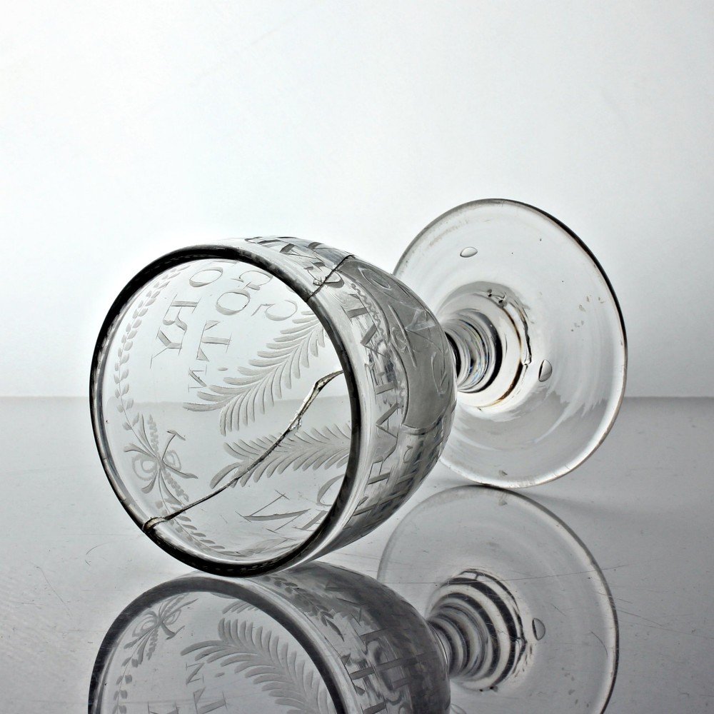 An antique clear glass rummer featuring hand-engraved naval motifs, text referencing Trafalgar, a short stem, and a circular foot. View V