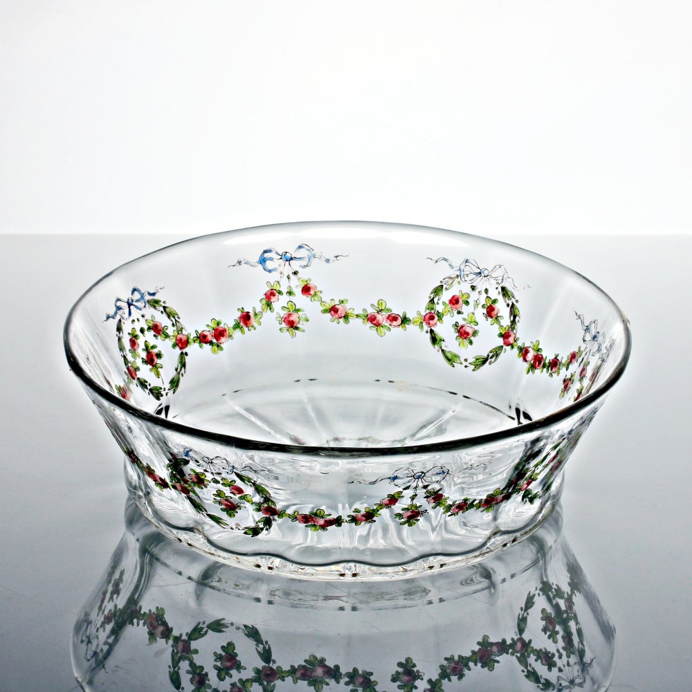 An oval clear glass bowl featuring hand-painted enamelled garlands of red roses, green foliage, and blue ribbons along the exterior with a gilded rim. View II