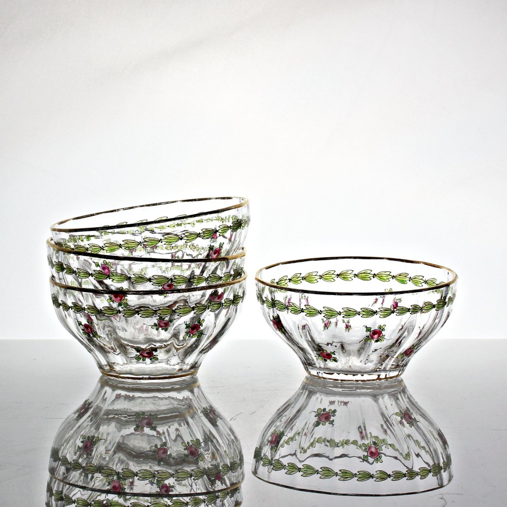 A set of four clear glass finger bowls decorated with hand-painted green leaf garlands, pink floral motifs, and gilded rims.