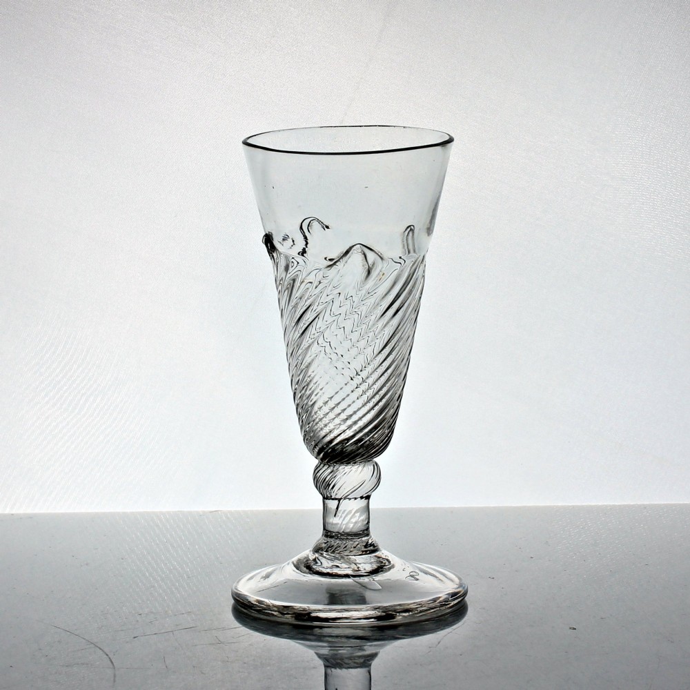 A clear Georgian hand-blown dwarf ale glass featuring a funnel-shaped bowl with diagonal flammiform moulding on a short knopped stem and conical foot. View II