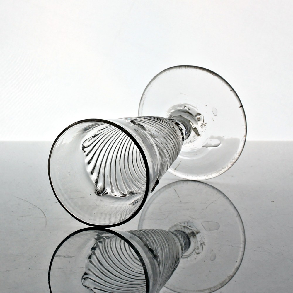 A clear Georgian hand-blown dwarf ale glass featuring a funnel-shaped bowl with diagonal flammiform moulding on a short knopped stem and conical foot. View III