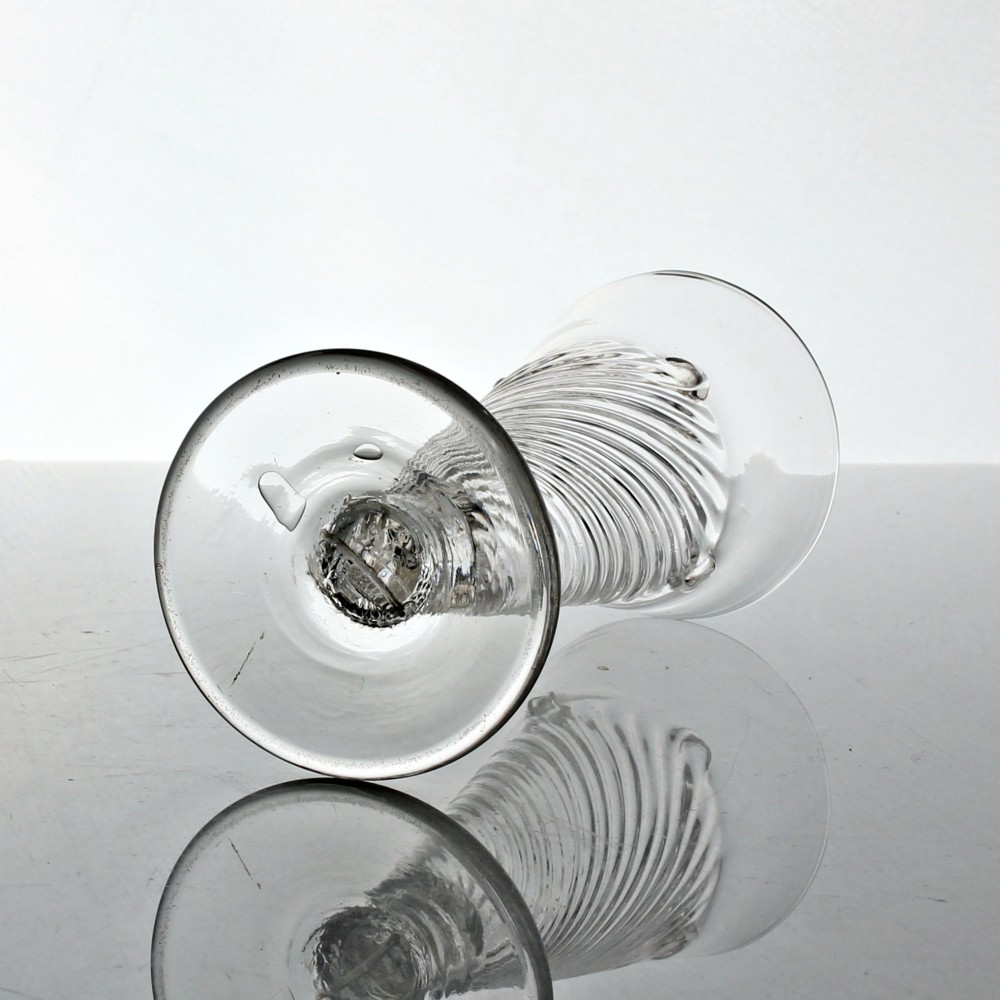 A clear Georgian hand-blown dwarf ale glass featuring a funnel-shaped bowl with diagonal flammiform moulding on a short knopped stem and conical foot. View IV