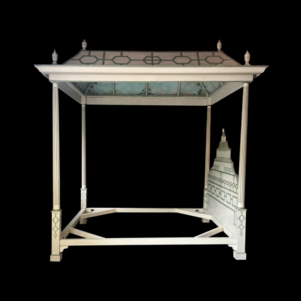 A cream-painted Edwardian four-poster bed frame featuring a pagoda-shaped headboard, decorative geometric fretwork, urn finials, and a painted canopy underside. View IV