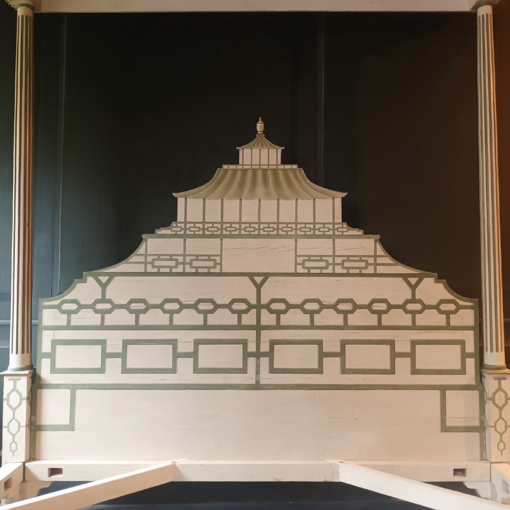 A cream-painted Edwardian four-poster bed frame featuring a pagoda-shaped headboard, decorative geometric fretwork, urn finials, and a painted canopy underside. View V