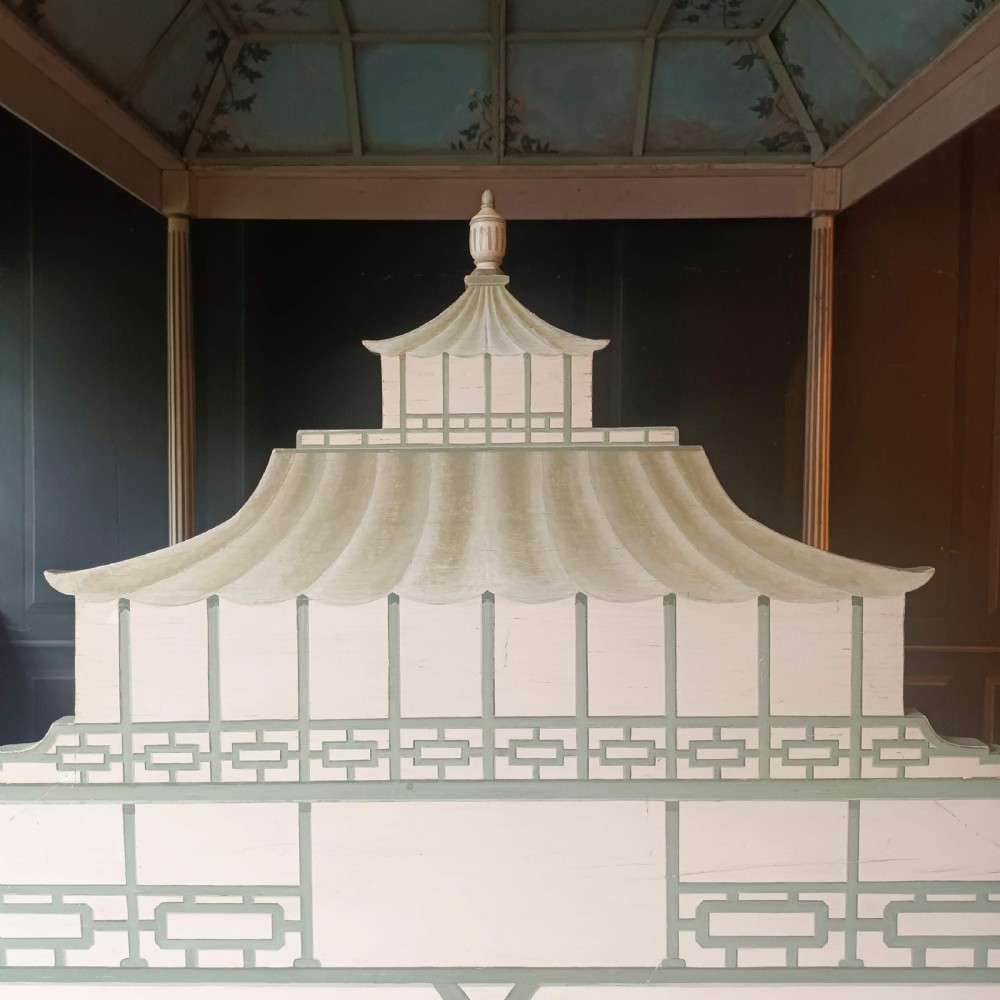 A cream-painted Edwardian four-poster bed frame featuring a pagoda-shaped headboard, decorative geometric fretwork, urn finials, and a painted canopy underside. View VI