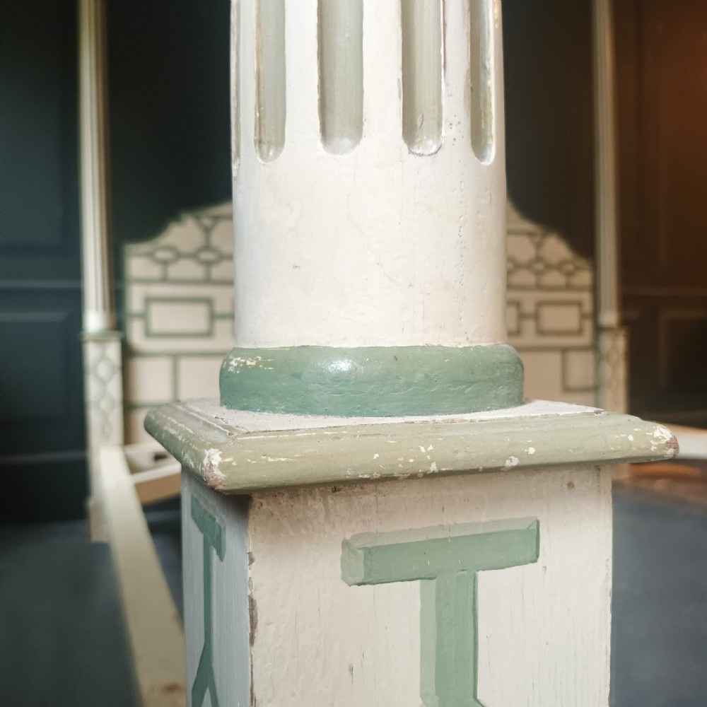 A cream-painted Edwardian four-poster bed frame featuring a pagoda-shaped headboard, decorative geometric fretwork, urn finials, and a painted canopy underside. View X