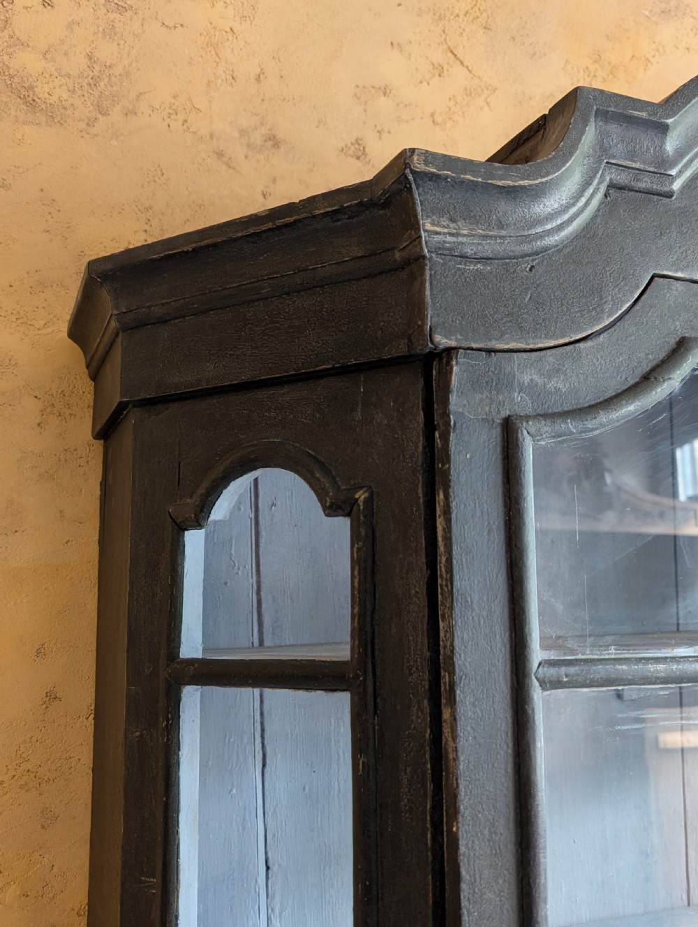 A tall dark grey painted Dutch vitrine cabinet featuring a shaped top hood, glazed upper doors, and three lower drawers with brass handles. View X