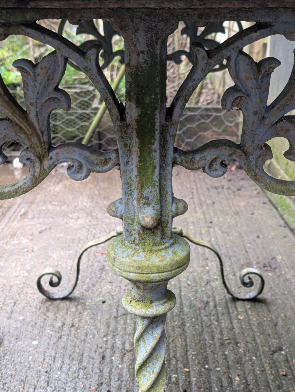 A rectangular grey veined marble top resting on a weathered cast iron base with twisted legs and scroll feet. View II
