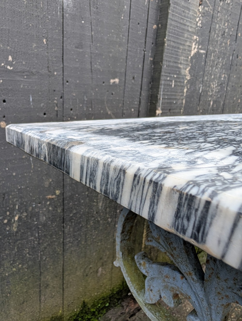 A rectangular grey veined marble top resting on a weathered cast iron base with twisted legs and scroll feet. View III