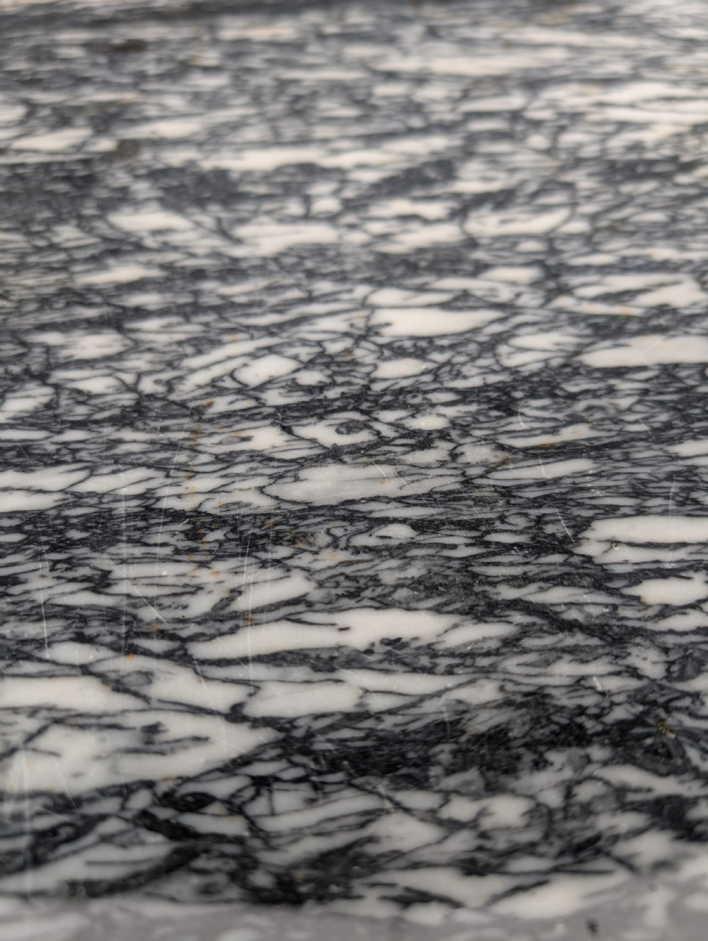 A rectangular grey veined marble top resting on a weathered cast iron base with twisted legs and scroll feet. View IV