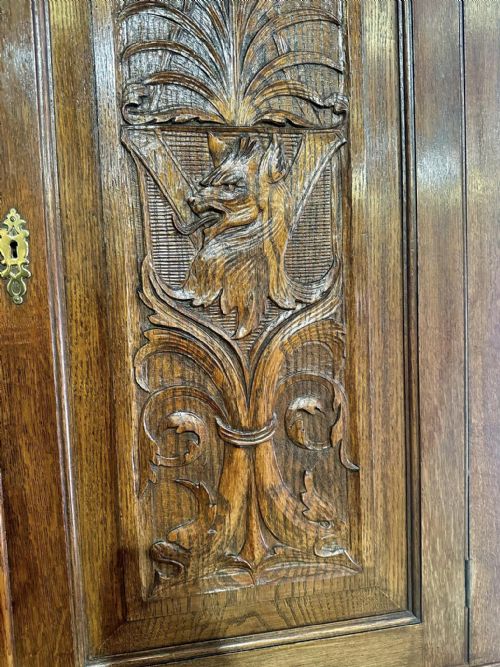 fig 5. A Victorian carved oak bureau bookcase featuring a scrolled pediment top, two carved upper doors, a slope-front writing surface with relief carvings, and four lower drawers with brass handles.