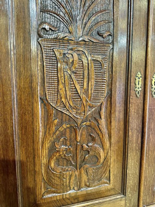 fig 6. A Victorian carved oak bureau bookcase featuring a scrolled pediment top, two carved upper doors, a slope-front writing surface with relief carvings, and four lower drawers with brass handles.