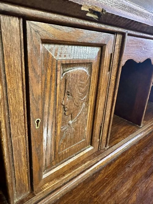 fig 7. A Victorian carved oak bureau bookcase featuring a scrolled pediment top, two carved upper doors, a slope-front writing surface with relief carvings, and four lower drawers with brass handles.