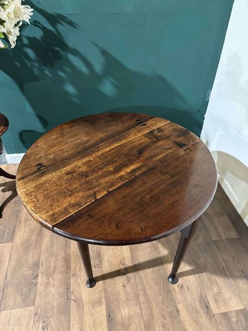 fig 1. An antique dark walnut drop leaf table with slender turned legs and side leaves folded down.