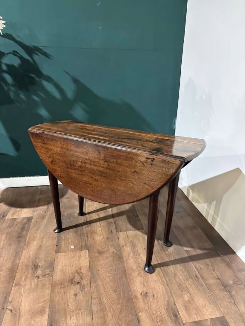 fig 2. An antique dark walnut drop leaf table with slender turned legs and side leaves folded down.