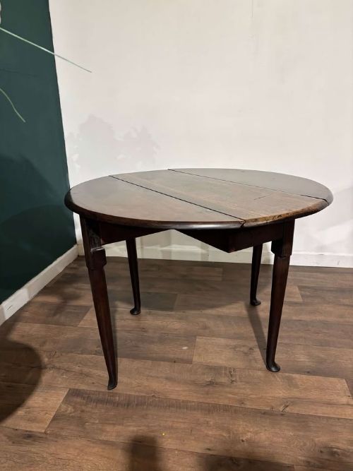 fig 4. An antique dark walnut drop leaf table with slender turned legs and side leaves folded down.