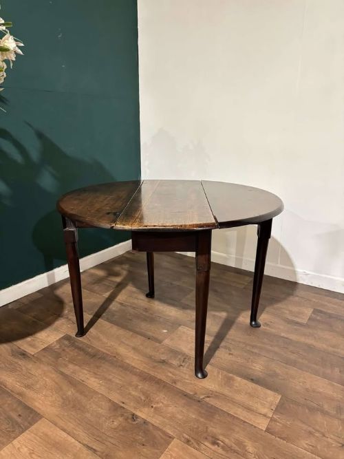 fig 6. An antique dark walnut drop leaf table with slender turned legs and side leaves folded down.