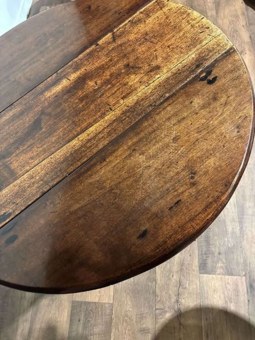 fig 7. An antique dark walnut drop leaf table with slender turned legs and side leaves folded down.