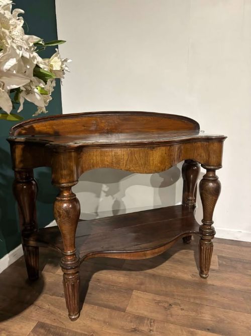 fig 4. A Victorian mahogany console table featuring a serpentine-contoured top, low splashback, turned and fluted legs, and a matching lower tier shelf.