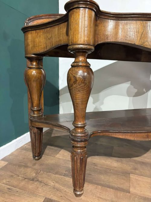 fig 6. A Victorian mahogany console table featuring a serpentine-contoured top, low splashback, turned and fluted legs, and a matching lower tier shelf.