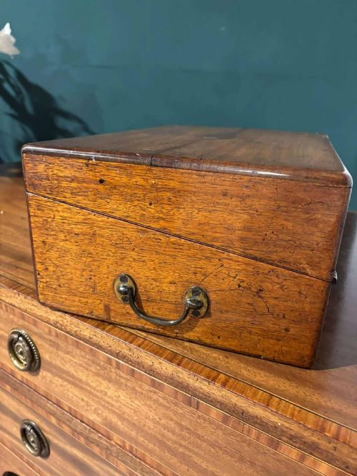 fig 1. A rectangular Victorian mahogany writing slope featuring brass side carrying handles and a brass keyhole escutcheon.