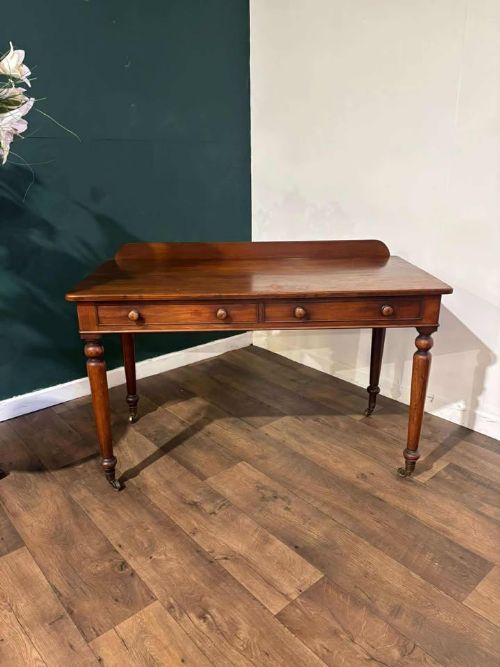 fig 3. A Victorian mahogany washstand featuring two drawers with wooden knob handles, a low gallery back, turned legs, and brass castors.