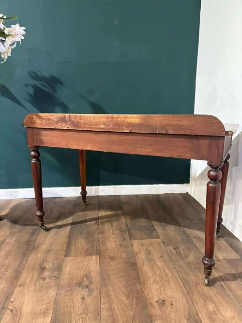 fig 4. A Victorian mahogany washstand featuring two drawers with wooden knob handles, a low gallery back, turned legs, and brass castors.
