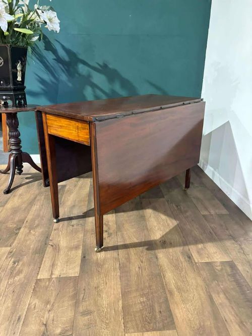 fig 3. A Victorian mahogany drop-leaf gateleg table with two extended leaves, straight legs, and small brass castors.
